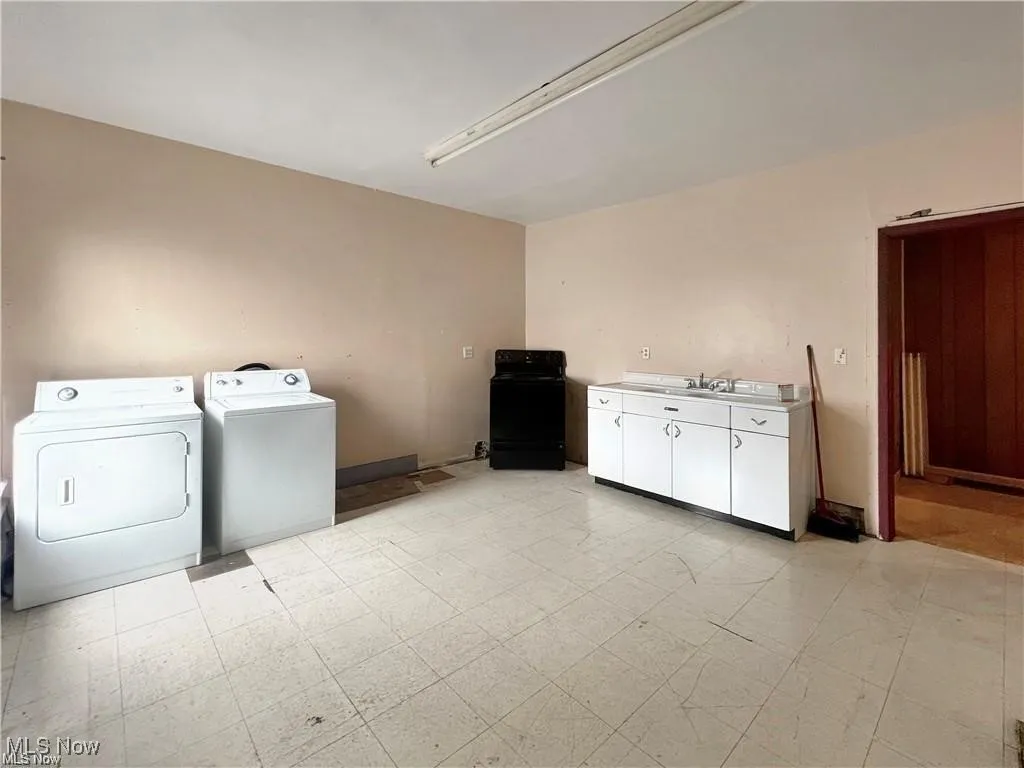 Laundry room featuring light floors, washing machine and dryer, and cabinet space