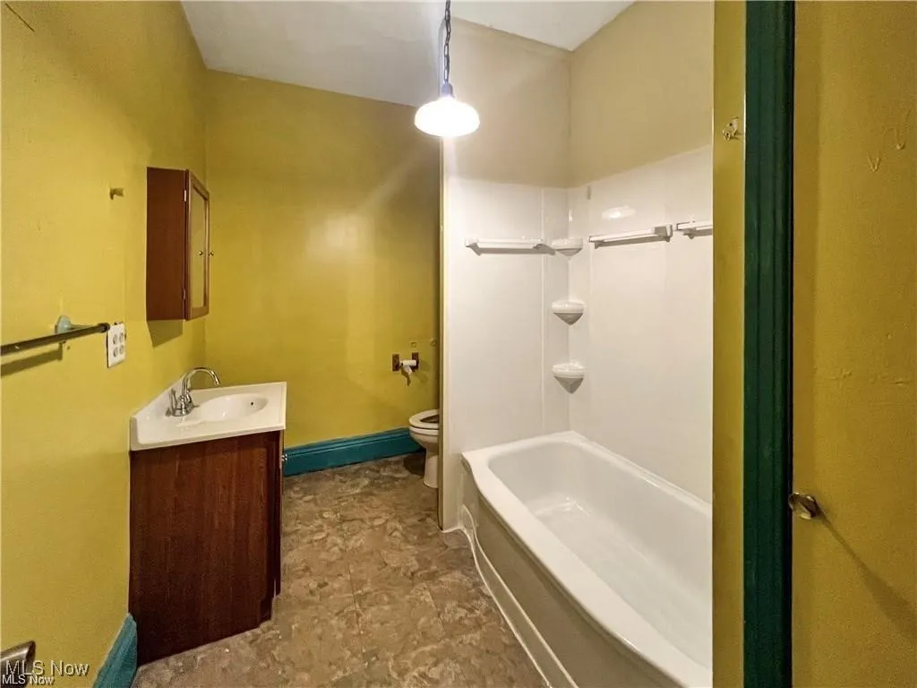 Full bath featuring a baseboard radiator, shower / bathing tub combination, toilet, vanity, and baseboards