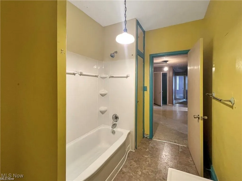 Bathroom featuring stone finish flooring and shower / tub combination