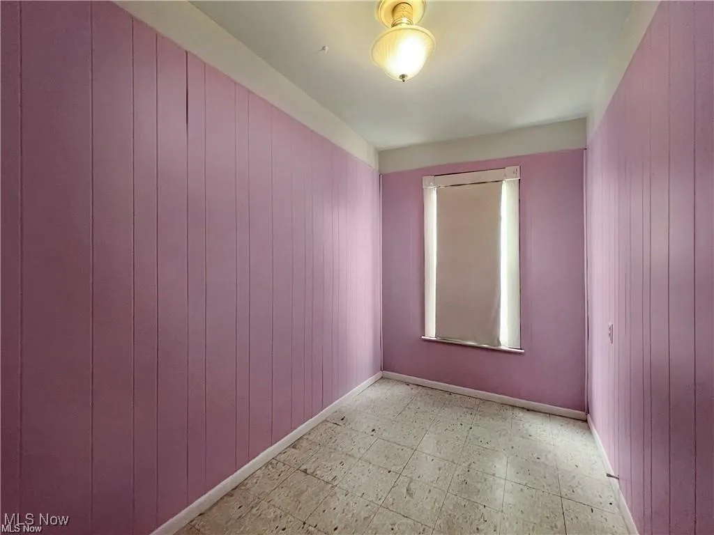 Spare room featuring wood walls and light floors