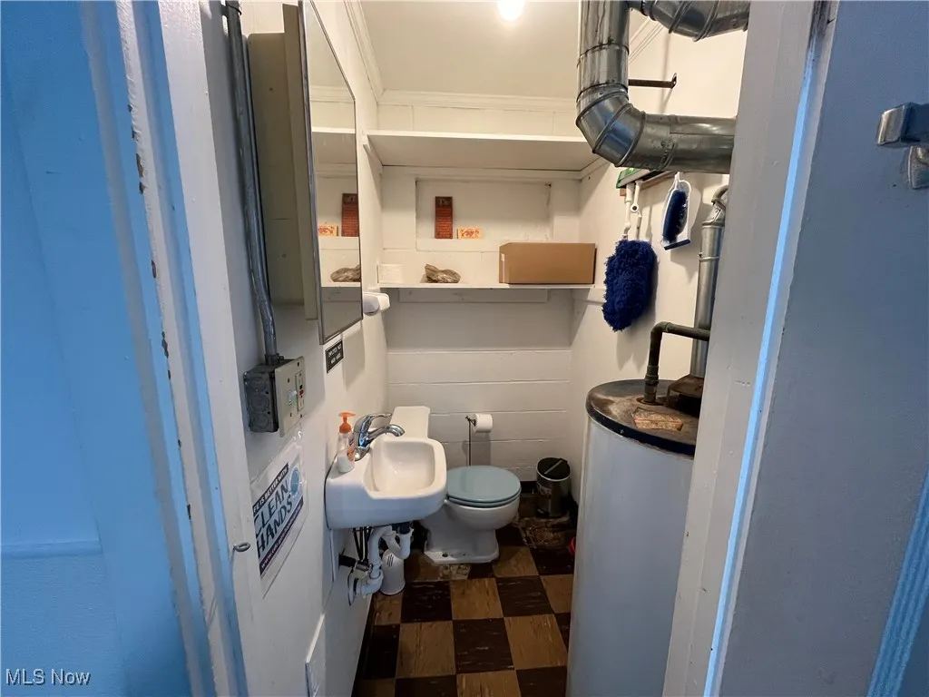 Bathroom featuring gas water heater, a sink, toilet, and tile patterned floors
