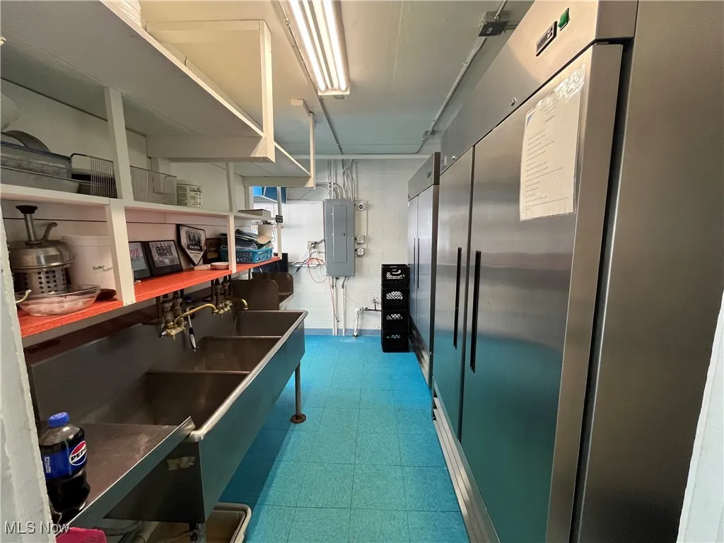 Kitchen featuring built in refrigerator, electric panel, and dark floors