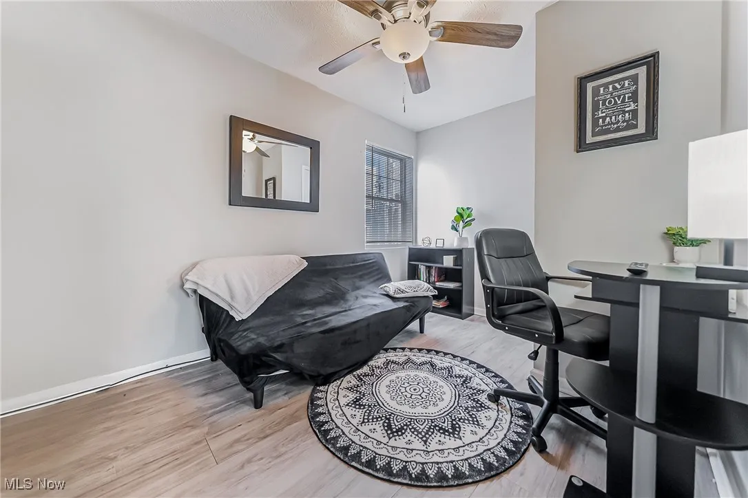 Home office with ceiling fan, light wood-style flooring, and baseboards