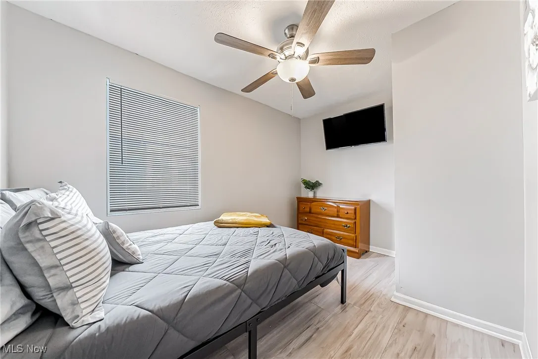 Bedroom with baseboards, a ceiling fan, and light wood-style floors