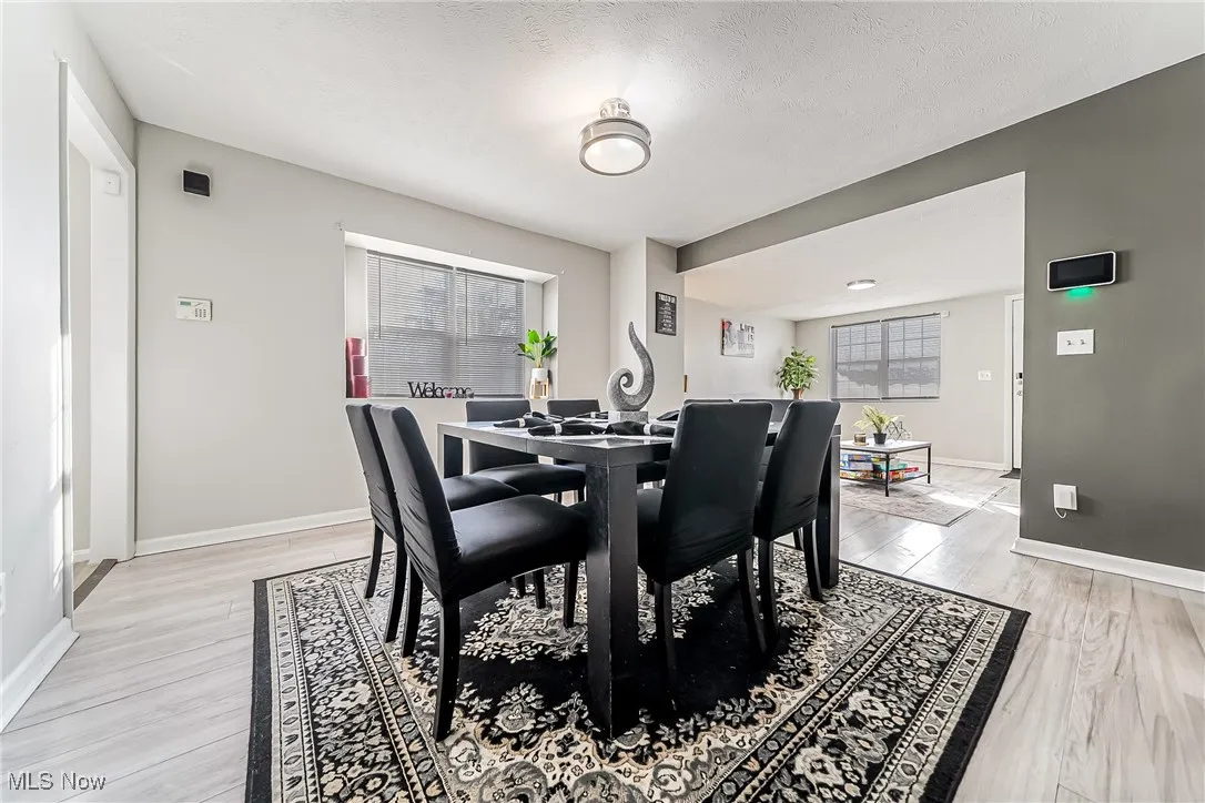 Dining room featuring a textured ceiling, light wood-type flooring, and baseboards