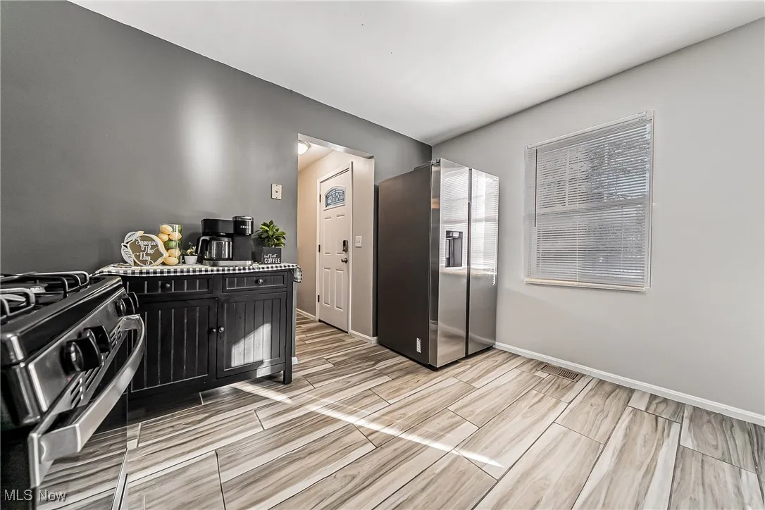 Kitchen featuring baseboards, dark cabinets, light countertops, stainless steel appliances, and wood finish floors