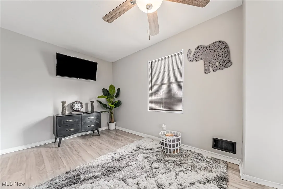 Living area with baseboards, visible vents, ceiling fan, and wood finished floors