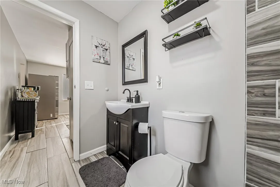 Half bathroom featuring toilet, wood tiled floor, baseboards, and vanity