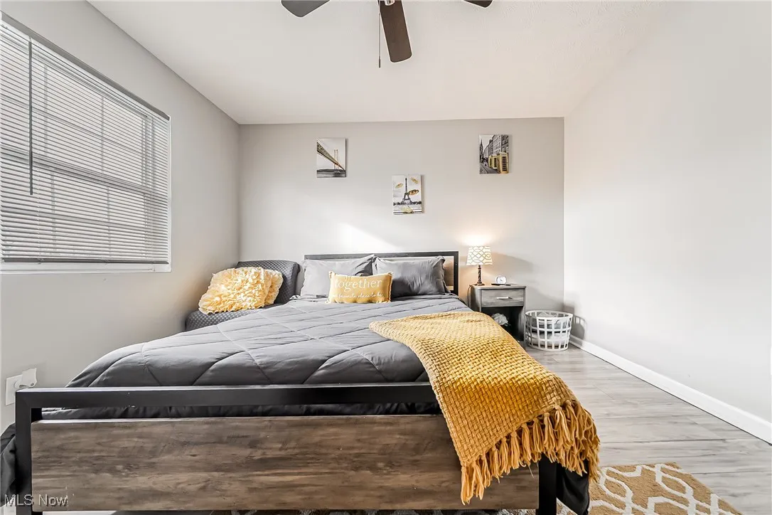 Bedroom featuring ceiling fan, baseboards, and wood finished floors