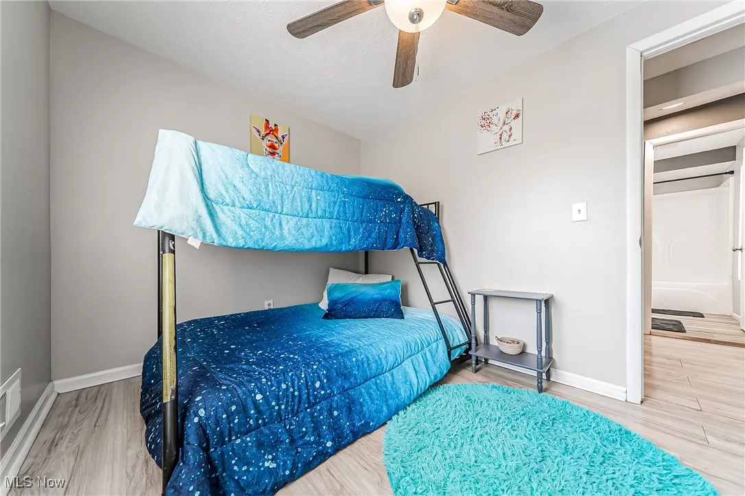 Bedroom with wood finished floors, a ceiling fan, and baseboards