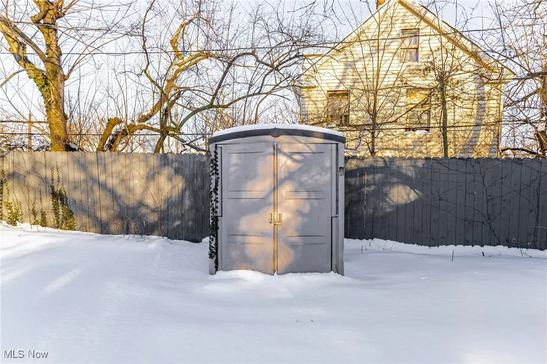 Snow covered structure featuring an outbuilding, a storage shed, and a fenced backyard