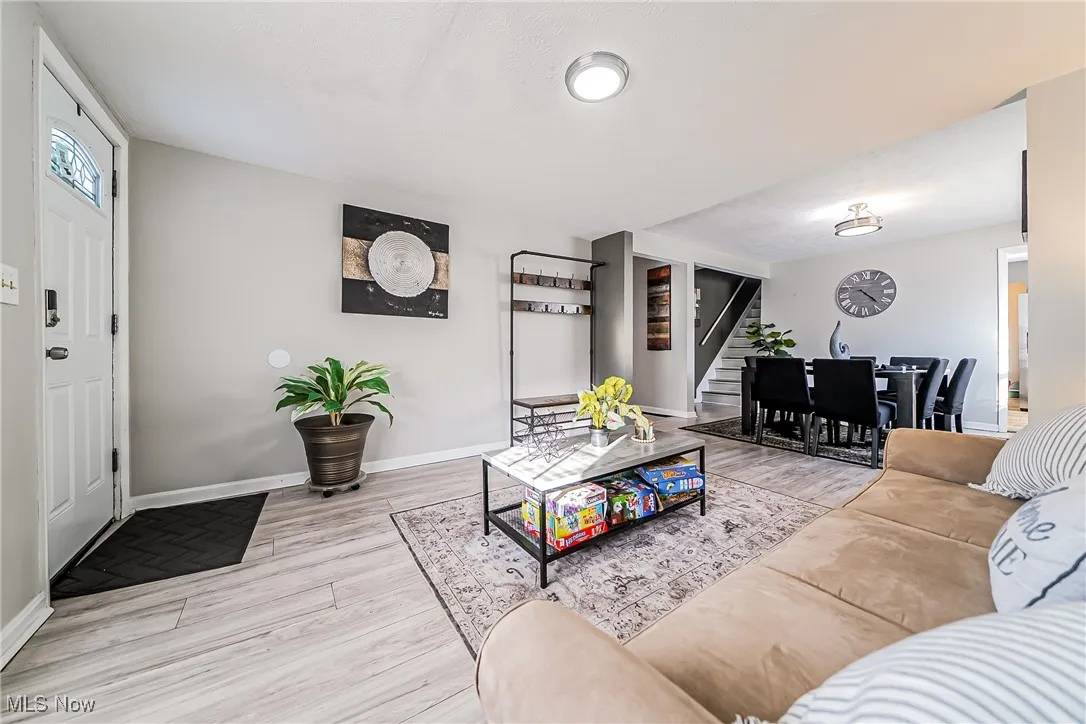 Living area with stairway, wood finished floors, and baseboards