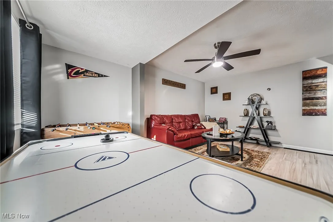 Playroom featuring a ceiling fan, a textured ceiling, and wood finished floors