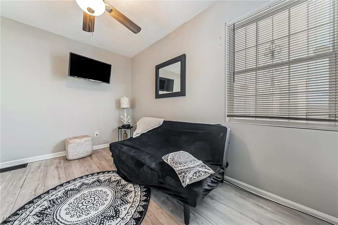 Living area with a ceiling fan, baseboards, visible vents, and wood finished floors