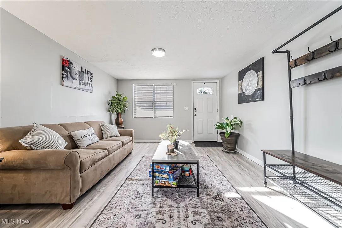 Living room featuring a textured ceiling, baseboards, and wood finished floors