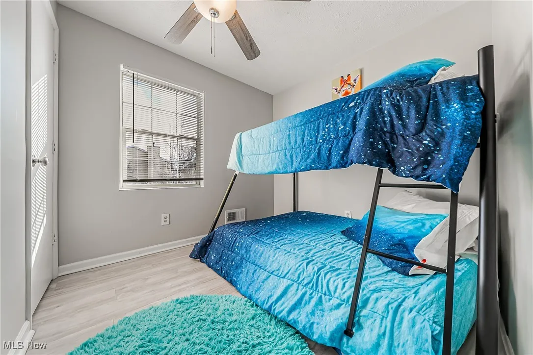Bedroom with visible vents, wood finished floors, a ceiling fan, and baseboards