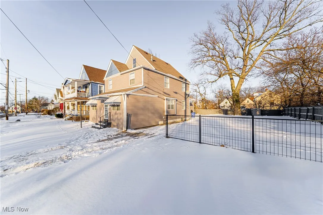 View of snow covered exterior featuring a residential view and fence
