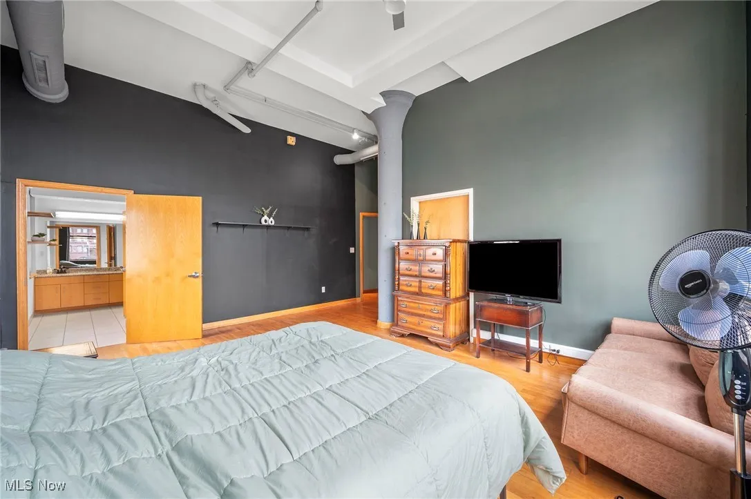 Bedroom featuring high vaulted ceiling, wood finished floors, and baseboards