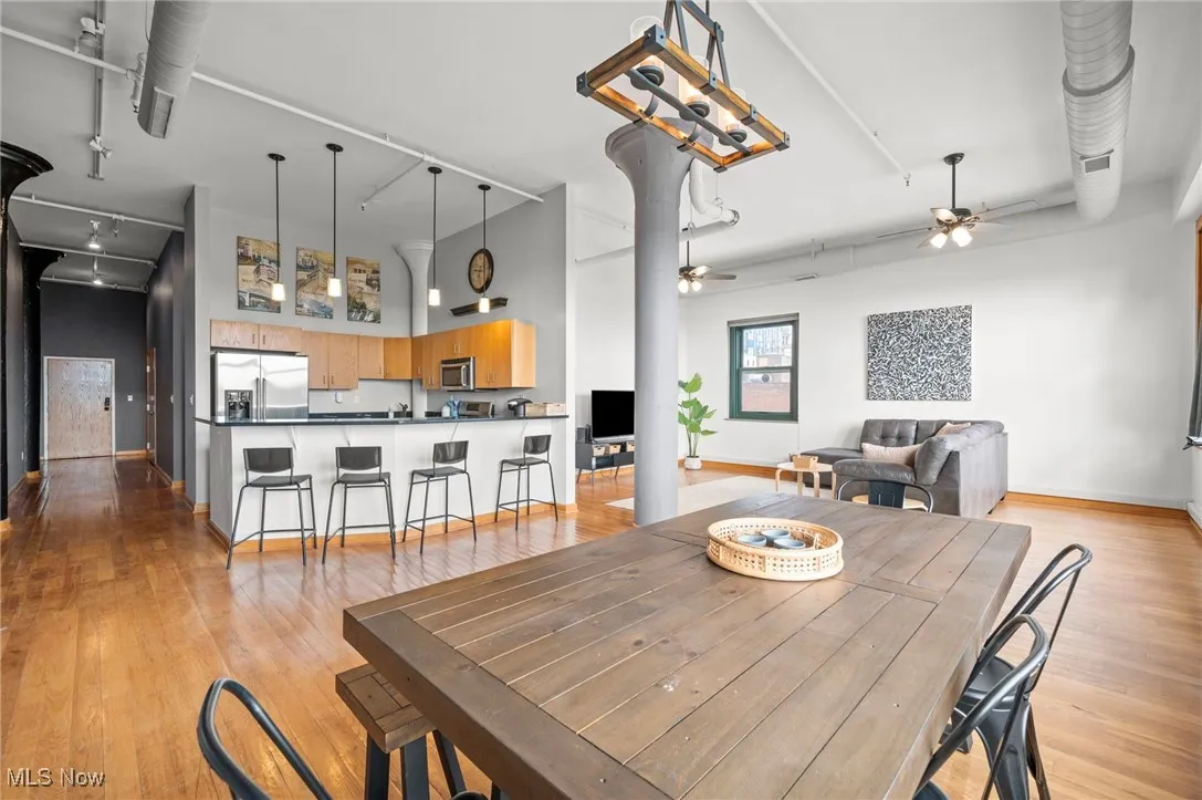 Dining area with a towering ceiling, ceiling fan, baseboards, and light wood-style flooring