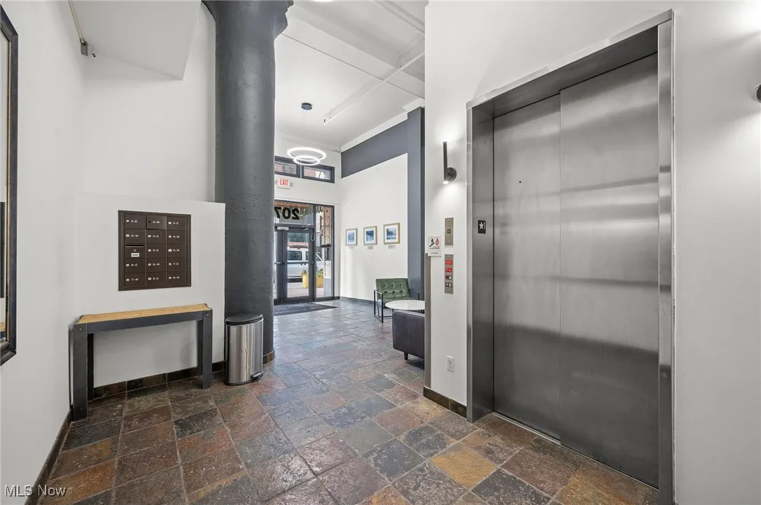 Corridor with stone tile floors, baseboards, ornamental molding, mail area, and elevator