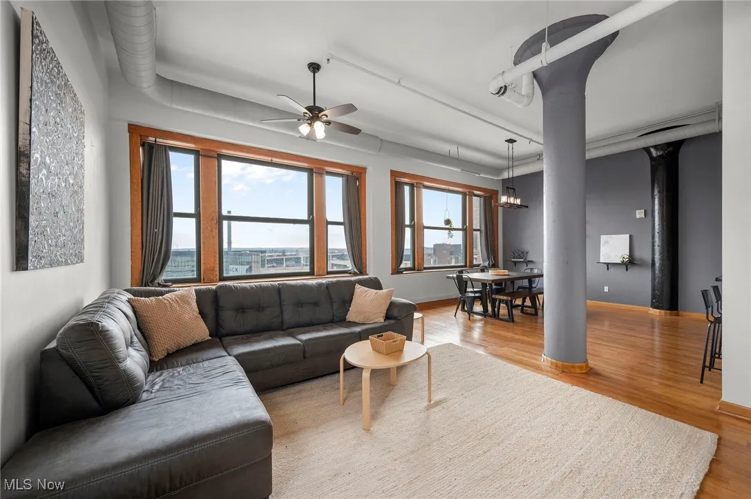 Living area featuring ceiling fan with notable chandelier, baseboards, and wood finished floors