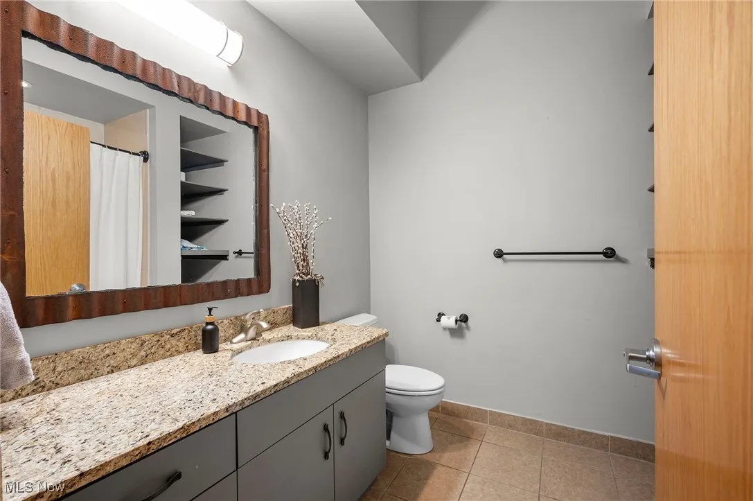 Full bathroom featuring toilet, tile patterned floors, vanity, baseboards, and a shower with curtain