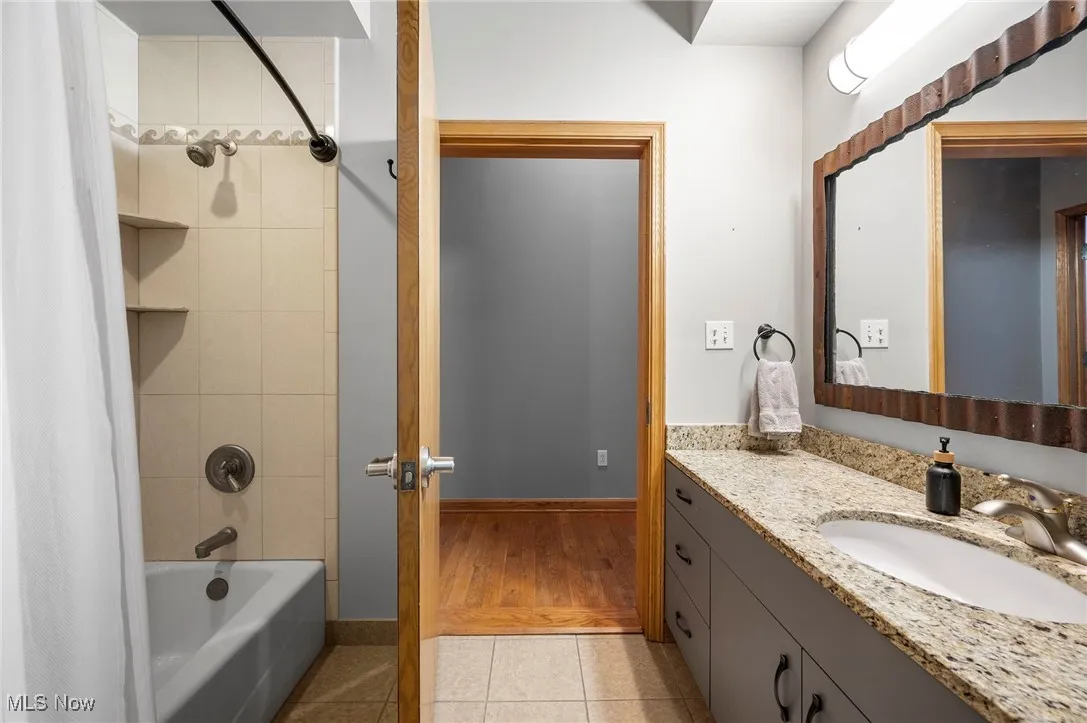 Full bathroom with shower / bath combination with curtain, tile patterned flooring, vanity, and baseboards