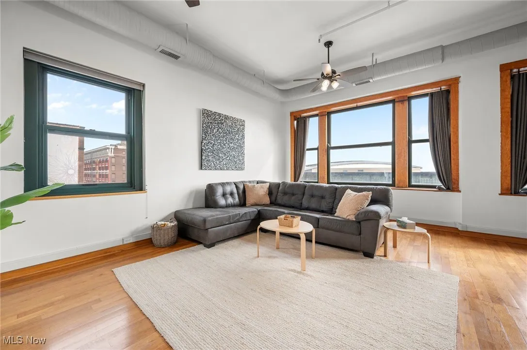 Living room featuring light wood-style floors, baseboards, visible vents, and a ceiling fan