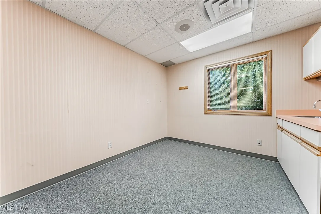 Unfurnished room with a paneled ceiling, baseboards, and a sink