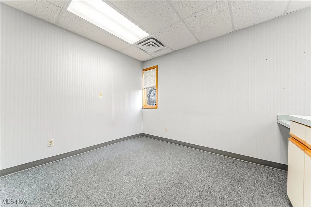 Empty room featuring a drop ceiling, visible vents, and baseboards