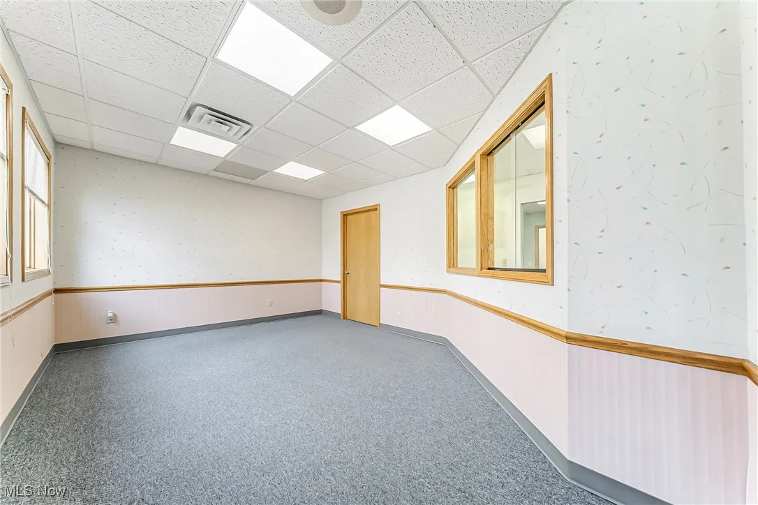 Spare room featuring a drop ceiling, wainscoting, and visible vents