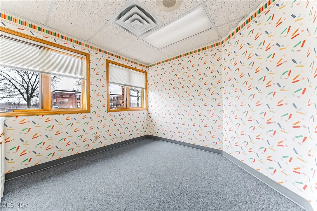 Empty room with a paneled ceiling, visible vents, and baseboards