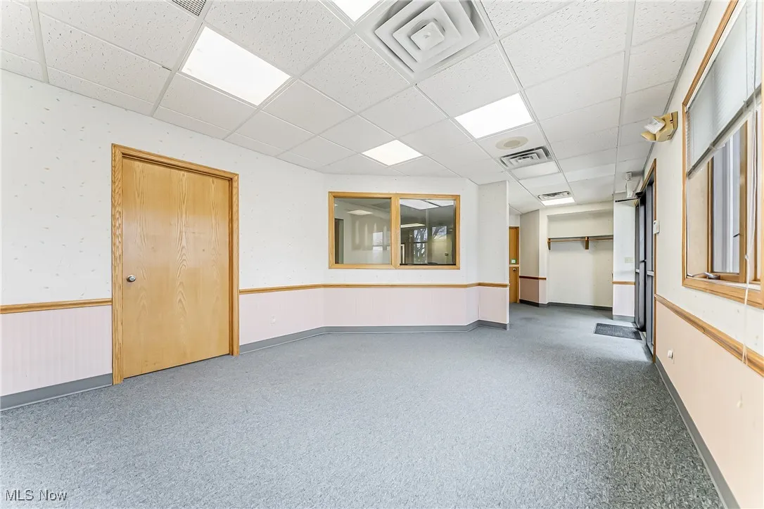 Carpeted spare room featuring a paneled ceiling, a wainscoted wall, visible vents, and wallpapered walls