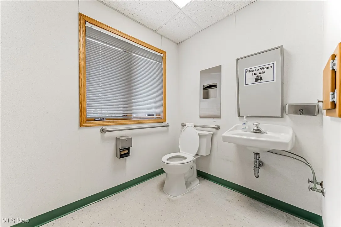 Bathroom with a paneled ceiling, a sink, baseboards, and toilet
