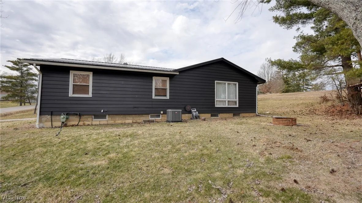 Rear view of property with cooling unit and a yard