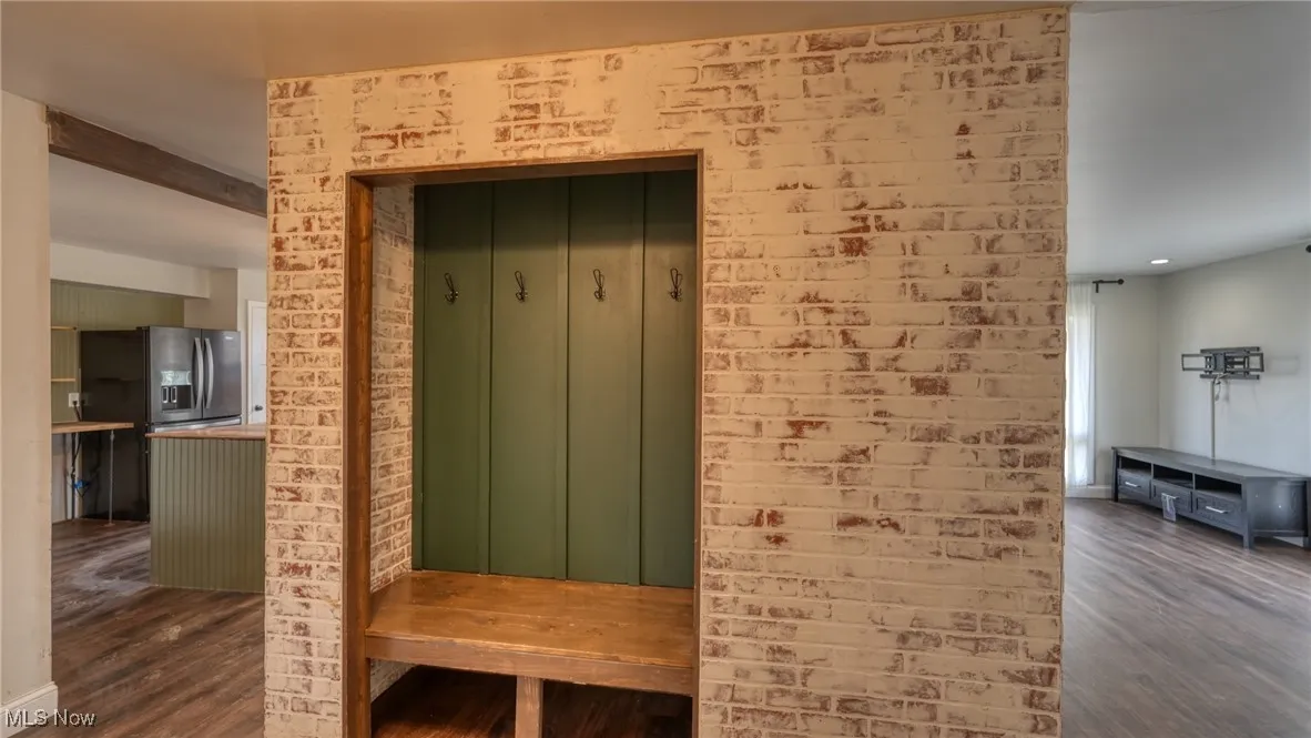 Mudroom featuring dark wood finished floors and brick wall