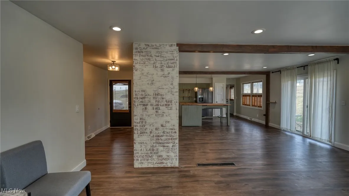 Unfurnished living room with baseboards, visible vents, dark wood-style flooring, and recessed lighting