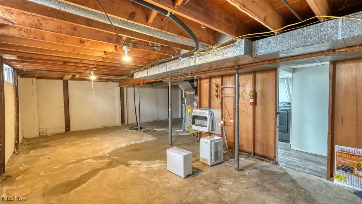 Unfinished basement featuring washer / clothes dryer and heating unit