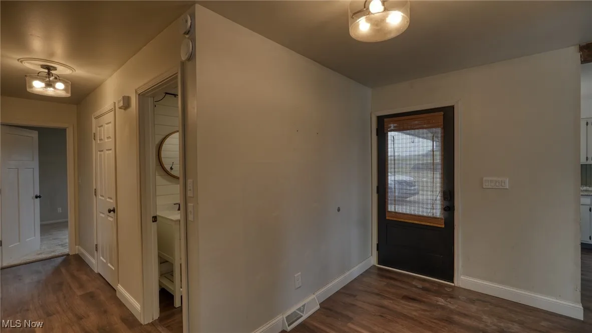 Foyer featuring visible vents, baseboards, and dark wood-style flooring
