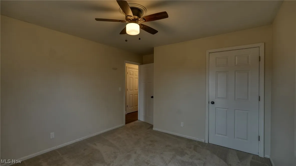 Unfurnished bedroom featuring carpet floors, baseboards, and a ceiling fan