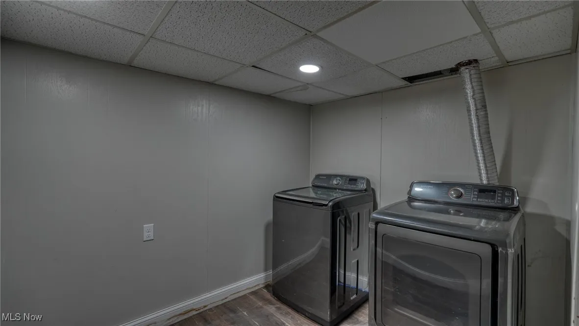 Washroom with baseboards, laundry area, wood finished floors, and washer and dryer