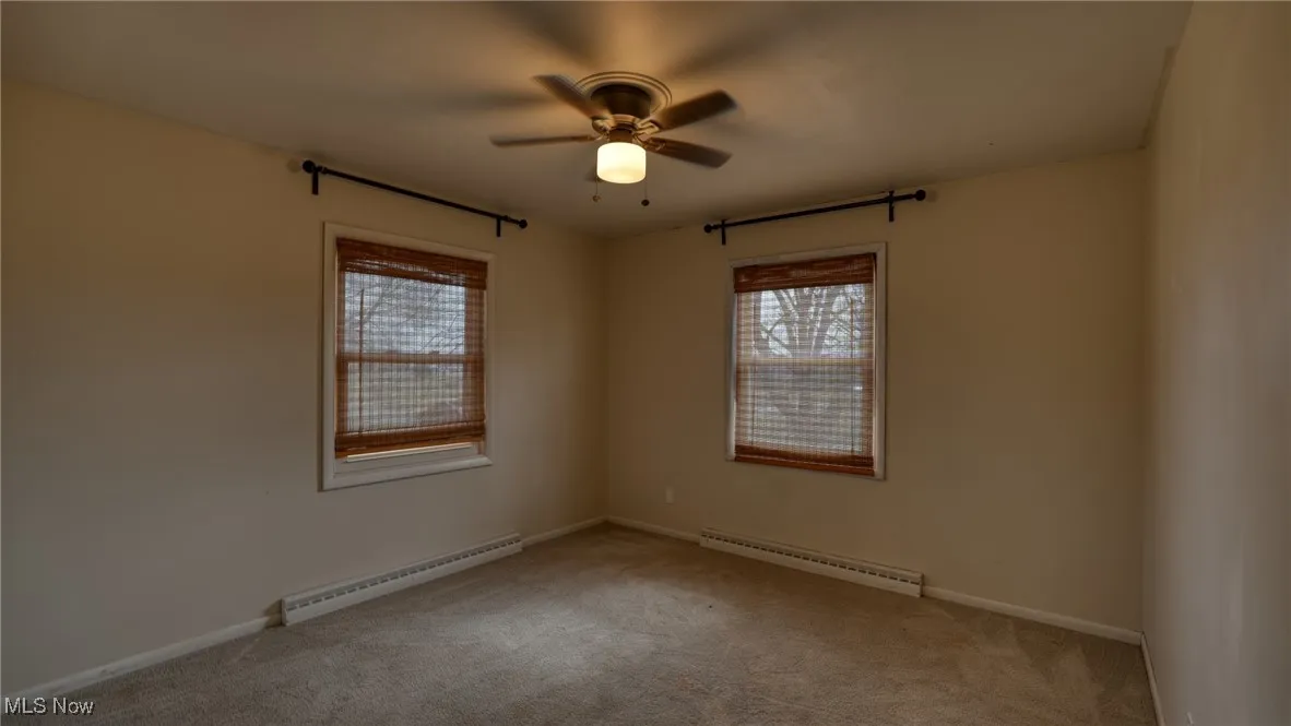 Spare room with carpet floors, a baseboard radiator, a baseboard heating unit, and ceiling fan