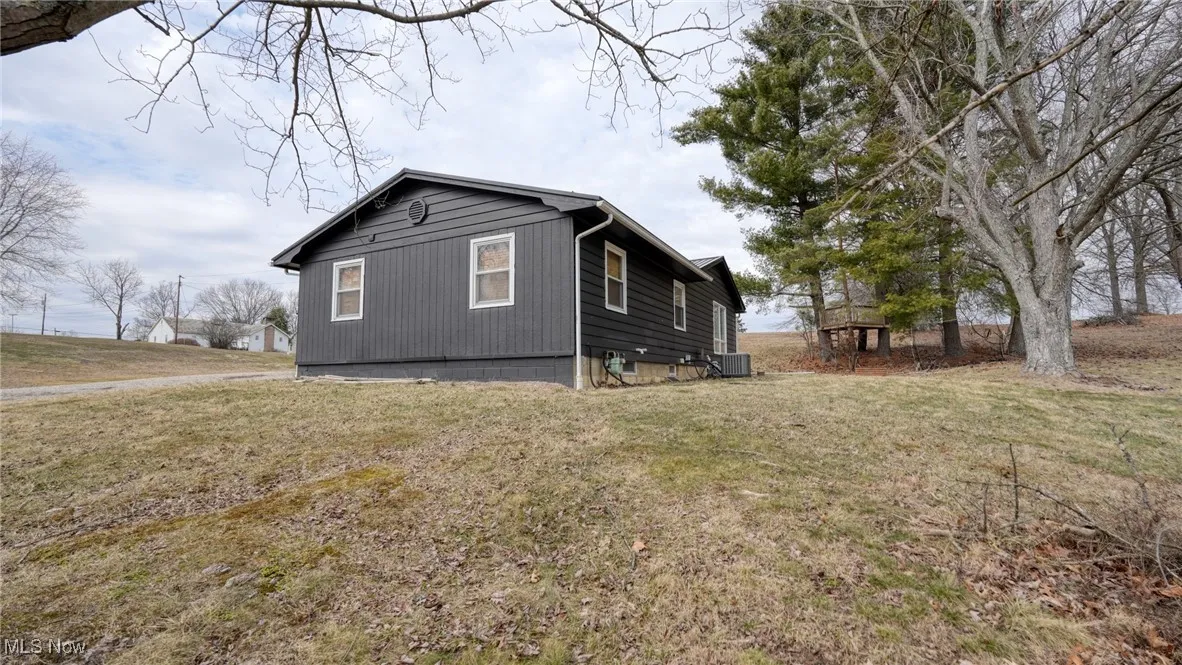 View of side of home with a lawn and cooling unit