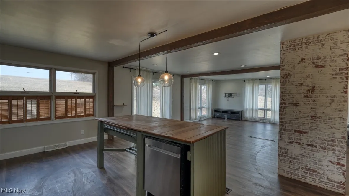 Kitchen featuring dark wood-style floors, beam ceiling, visible vents, open floor plan, and baseboards