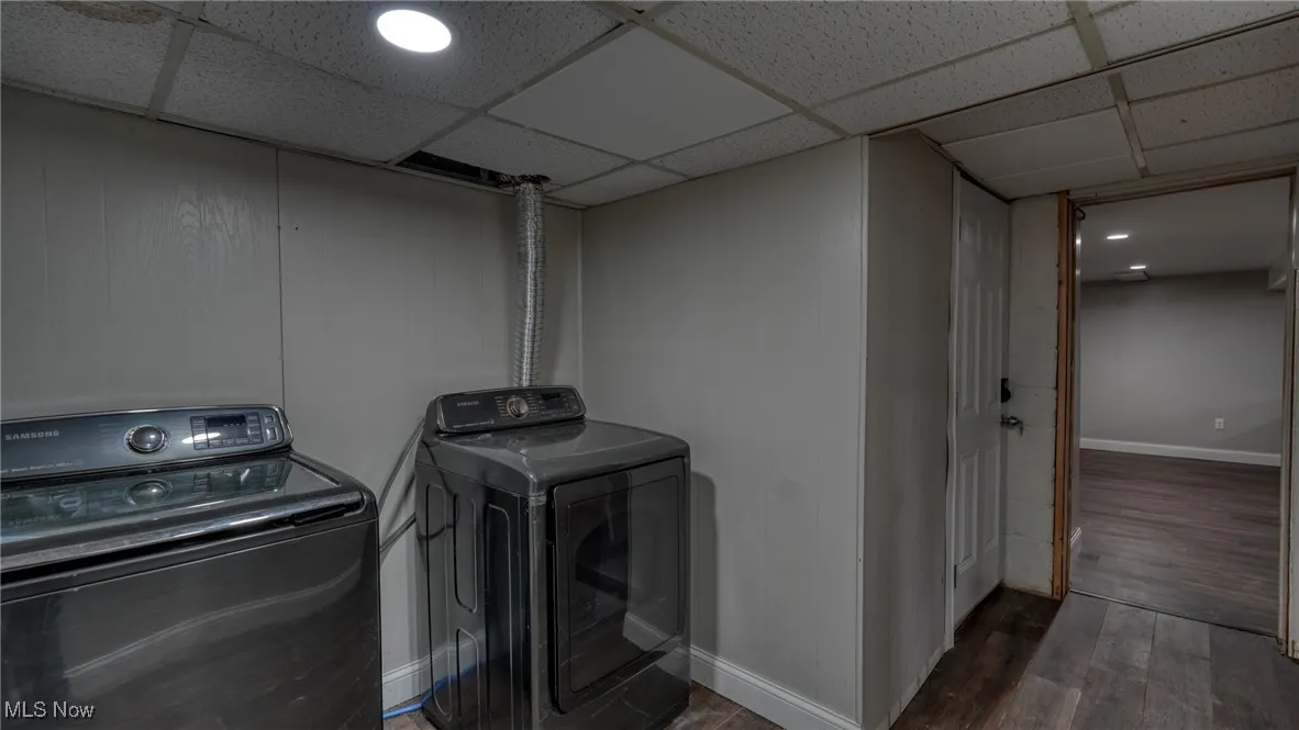 Washroom featuring baseboards, washing machine and clothes dryer, and wood finished floors