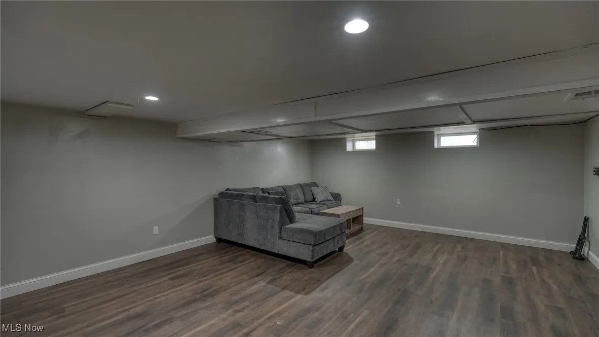 Living area with recessed lighting, dark wood-style flooring, visible vents, and baseboards