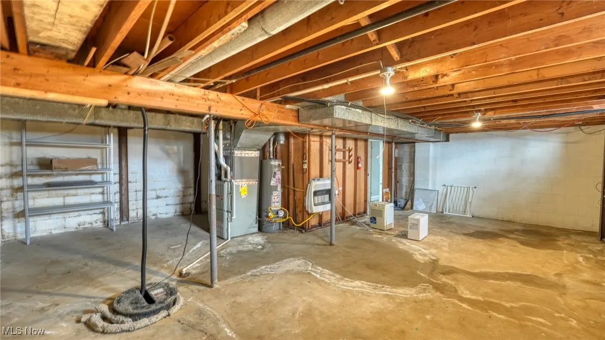 Unfinished below grade area featuring water heater and heating unit