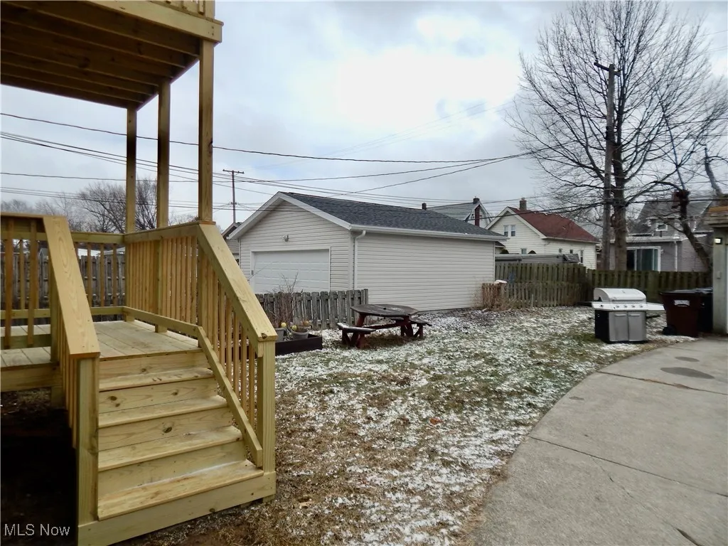 View of home's exterior with a detached garage, stairway, an outbuilding, fence, and a deck