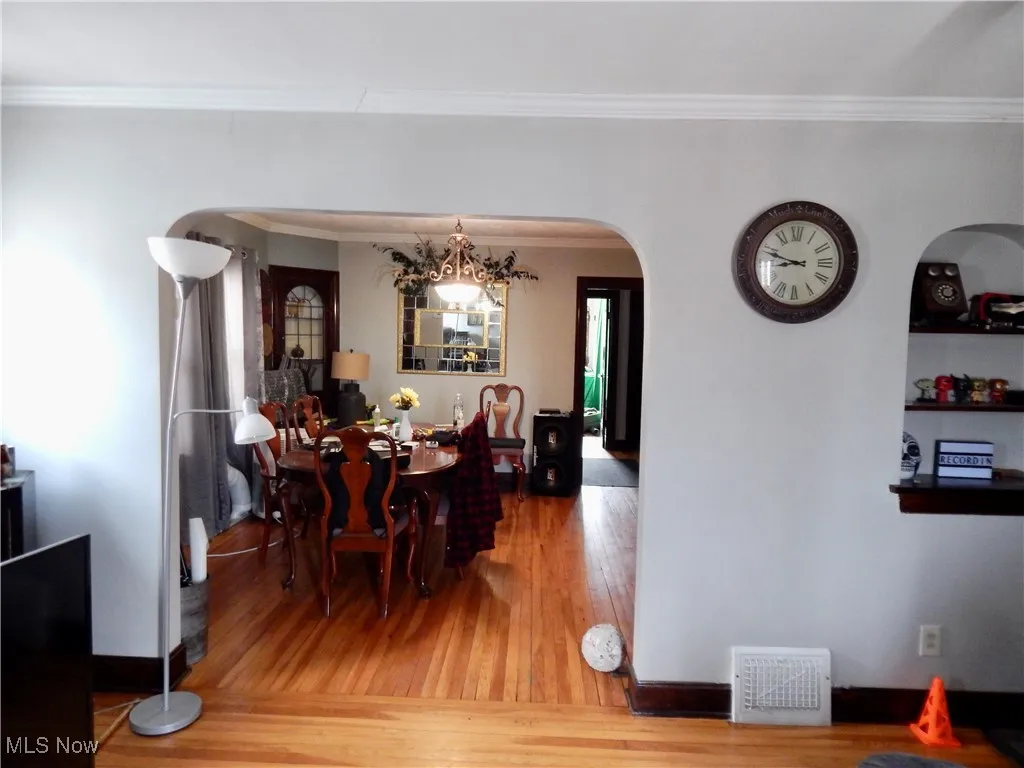 Upstairs unit Dining space featuring arched walkways, hardwood floors, and ornamental molding