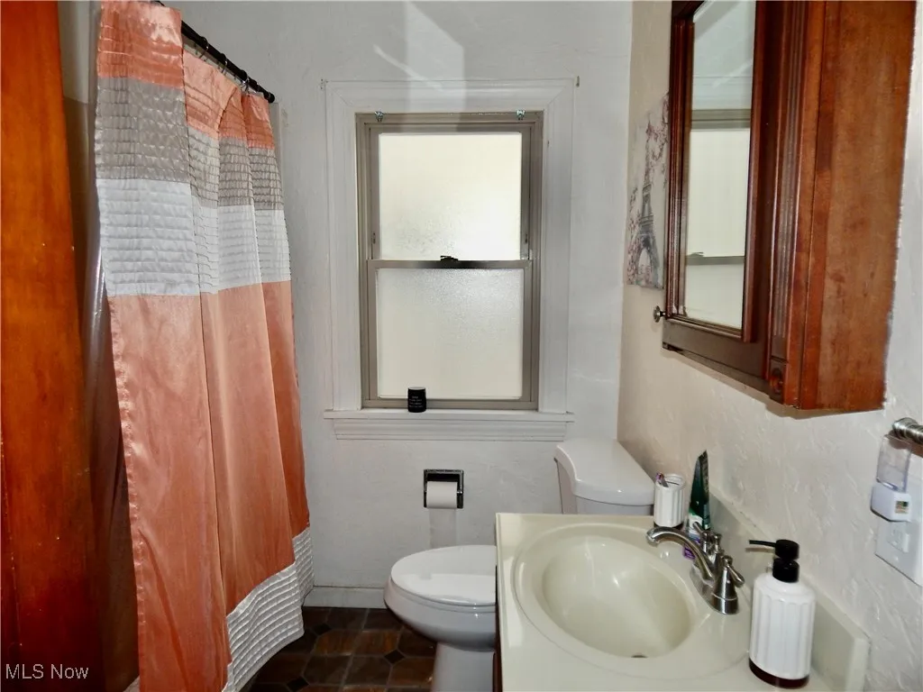 Bathroom featuring a bathtub/shower, a sink, toilet, and tile patterned floors